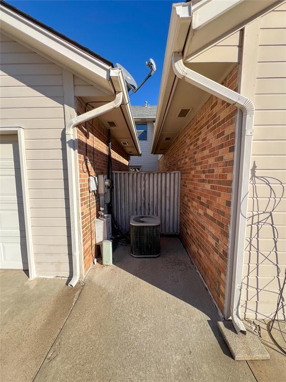 exterior space with central AC unit, fence, and brick siding