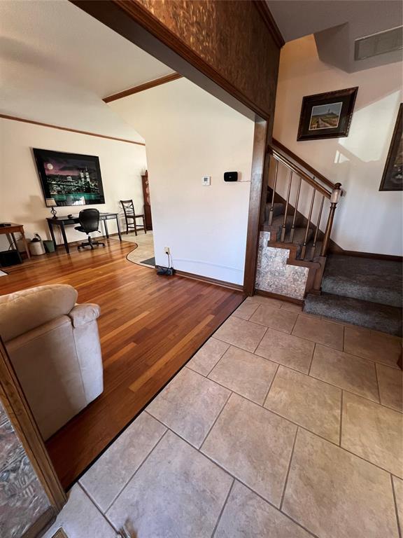 entryway with light wood finished floors, stairway, and visible vents