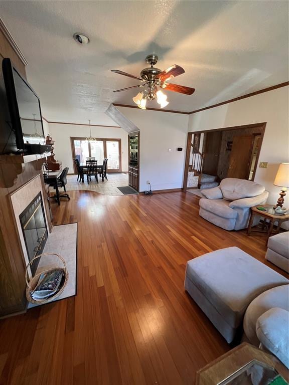 living room with baseboards, a tile fireplace, ceiling fan, wood finished floors, and crown molding