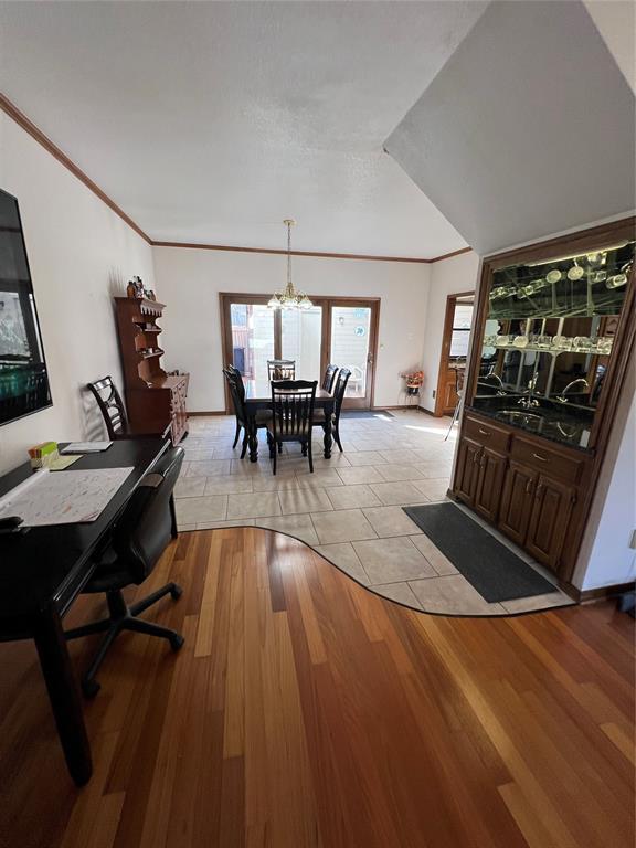 dining space featuring light wood-style flooring, ornamental molding, and a notable chandelier