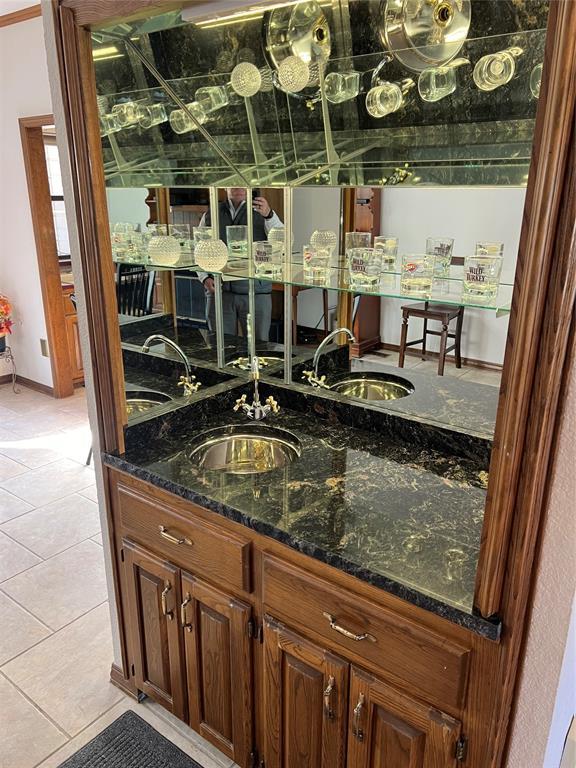 bar with wet bar, a sink, and light tile patterned floors