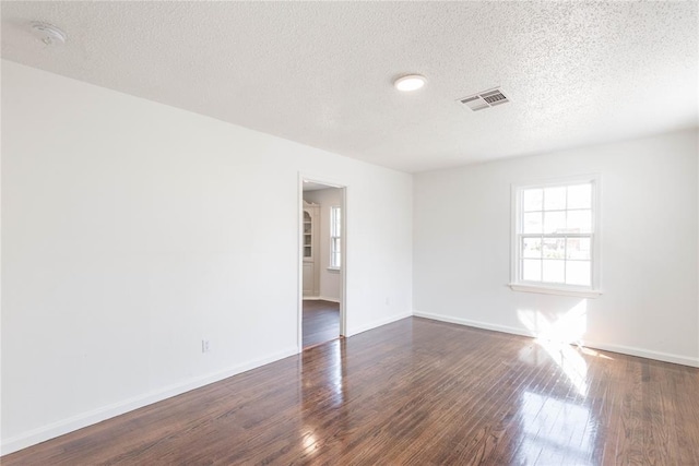 empty room featuring dark wood-type flooring and a textured ceiling