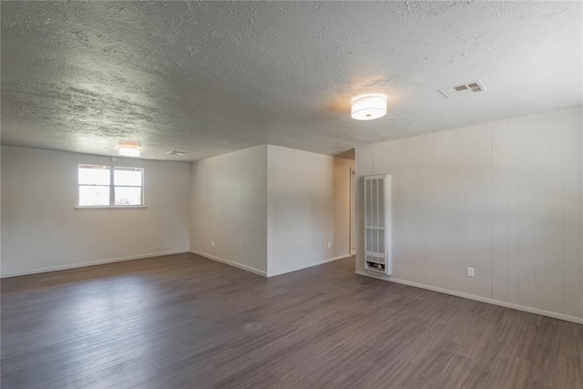 empty room with a textured ceiling and dark hardwood / wood-style flooring