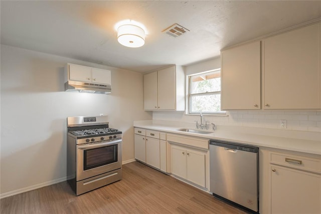 kitchen with stainless steel appliances, light hardwood / wood-style floors, backsplash, and sink