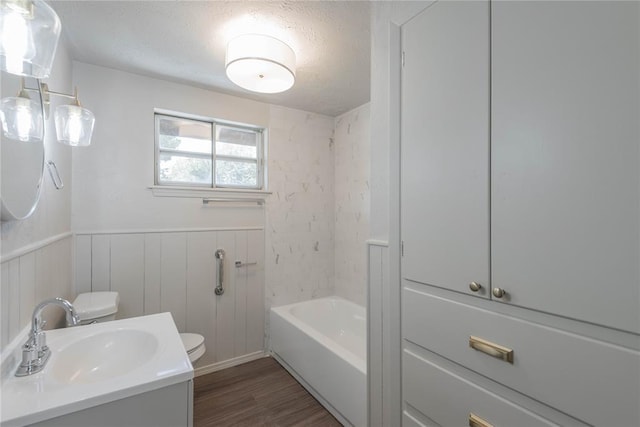 bathroom with wood-type flooring, toilet, vanity, and a textured ceiling