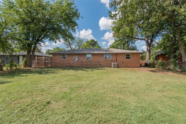 back of property with a yard and central AC