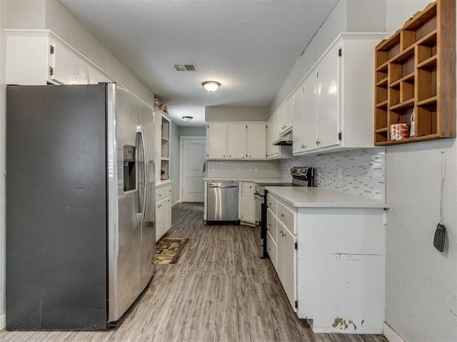 kitchen with tasteful backsplash, white cabinets, appliances with stainless steel finishes, and hardwood / wood-style flooring