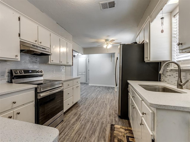 kitchen with stainless steel electric range oven, ceiling fan, light wood-type flooring, white cabinets, and sink