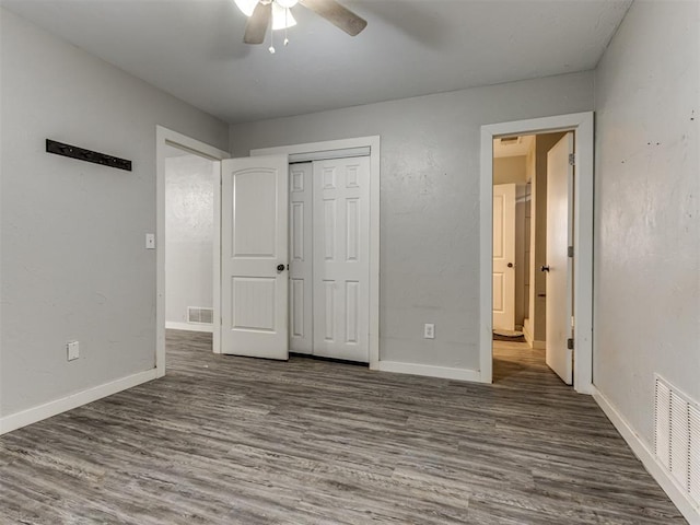 unfurnished bedroom with ceiling fan, a closet, and dark wood-type flooring