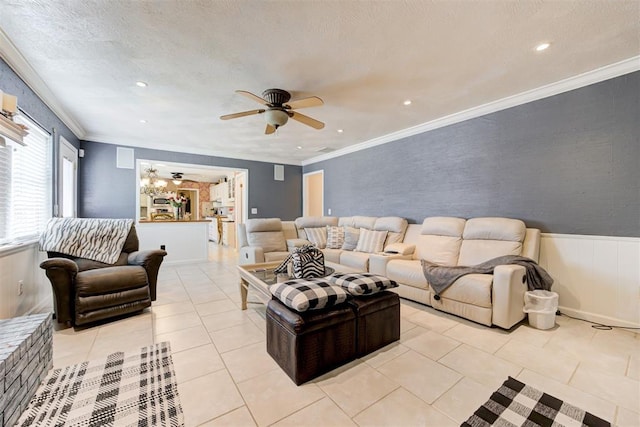 living room with a textured ceiling, ceiling fan, light tile patterned floors, and ornamental molding