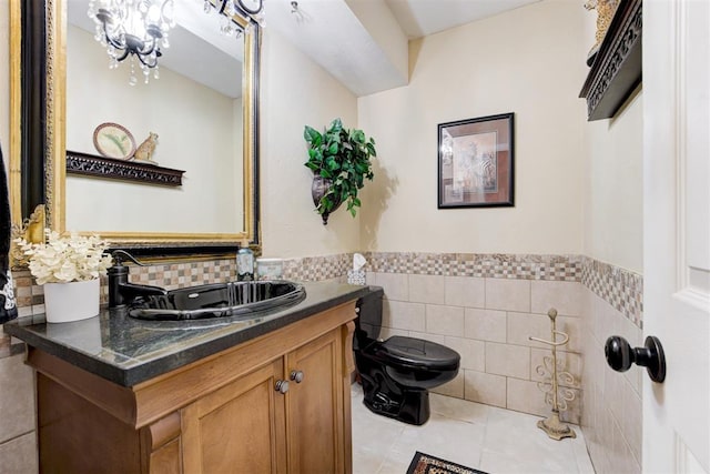 bathroom with toilet, vanity, tile walls, tile patterned floors, and an inviting chandelier