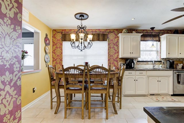 dining area with sink, light tile patterned flooring, and ceiling fan with notable chandelier