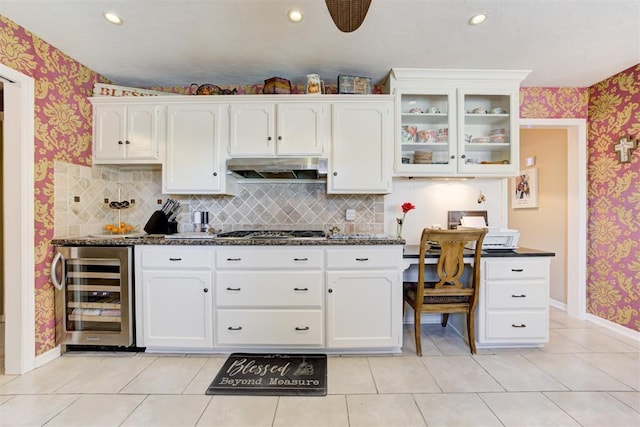 kitchen featuring light tile patterned floors, beverage cooler, white cabinetry, and backsplash