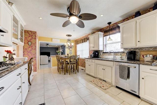 kitchen featuring decorative light fixtures, light tile patterned floors, stainless steel dishwasher, and dark stone countertops