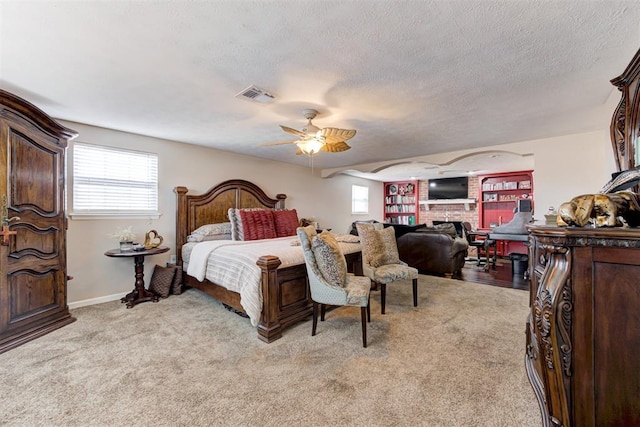 carpeted bedroom with a textured ceiling, ceiling fan, and a brick fireplace