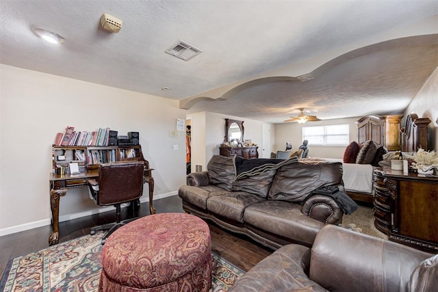 living room with ceiling fan, dark wood-type flooring, and a textured ceiling