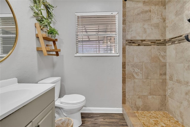 bathroom with vanity, hardwood / wood-style flooring, toilet, and tiled shower