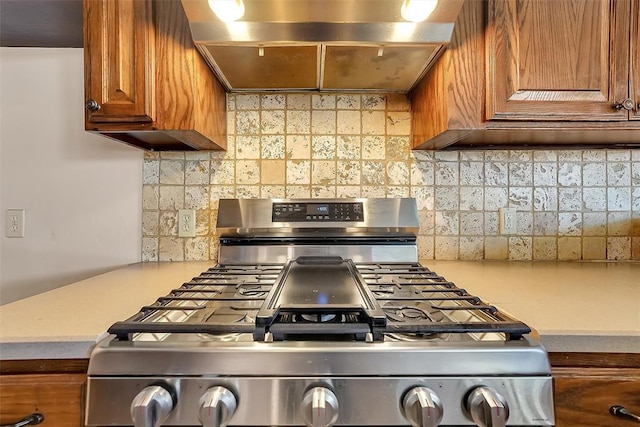 kitchen with ventilation hood, stainless steel gas stove, and tasteful backsplash