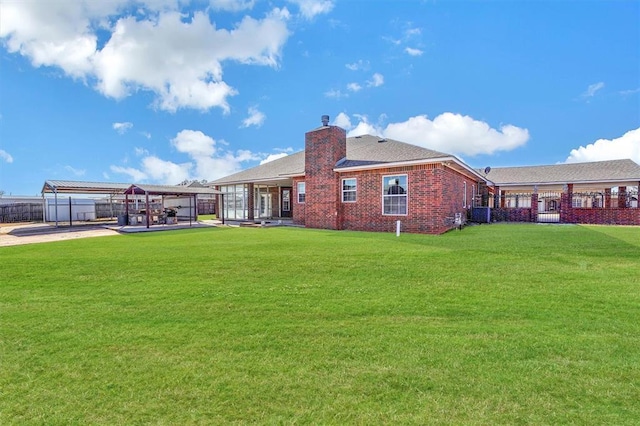 back of property with a carport and a yard