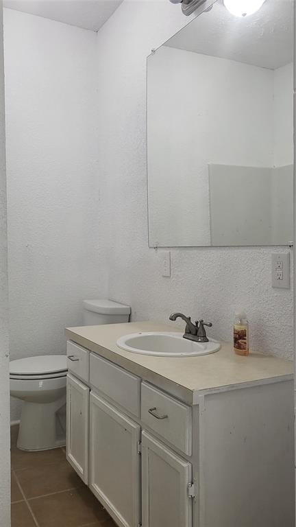 bathroom with toilet, vanity, and tile patterned floors