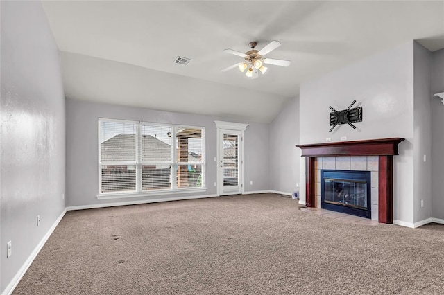 unfurnished living room featuring vaulted ceiling, ceiling fan, carpet floors, and a tile fireplace