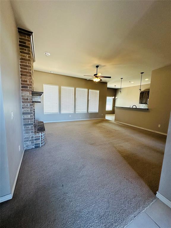 unfurnished living room featuring ceiling fan, carpet flooring, and a fireplace