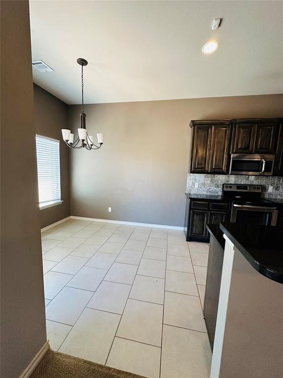 kitchen with light tile patterned floors, backsplash, a notable chandelier, and stainless steel appliances