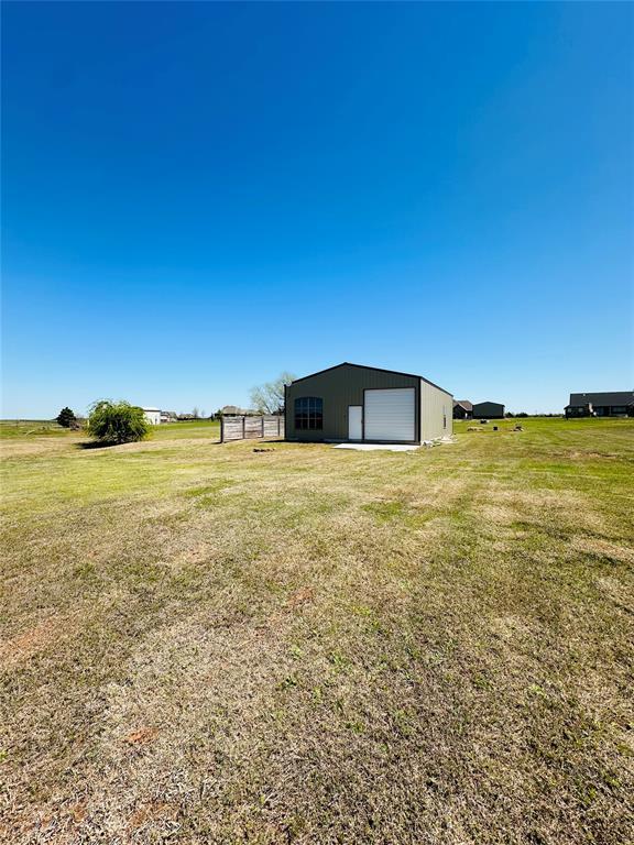 view of yard featuring an outbuilding, a rural view, and a garage