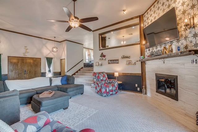 living room featuring ceiling fan, a tiled fireplace, crown molding, and carpet floors