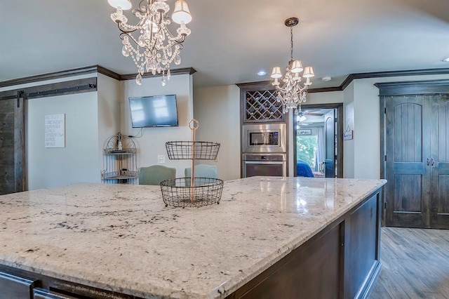 kitchen featuring hanging light fixtures, a barn door, appliances with stainless steel finishes, and an inviting chandelier