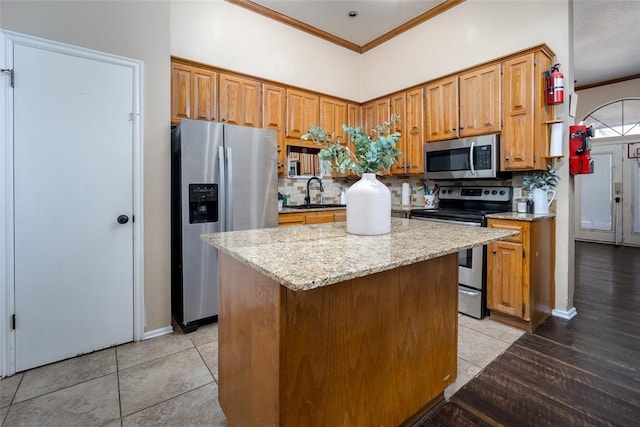 kitchen featuring decorative backsplash, appliances with stainless steel finishes, sink, and a center island