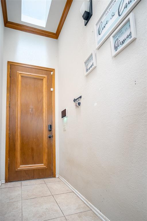 entryway featuring light tile patterned floors and crown molding