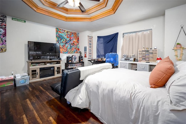 bedroom with ceiling fan, dark hardwood / wood-style floors, a raised ceiling, and crown molding