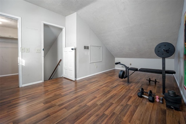 exercise room with vaulted ceiling, dark hardwood / wood-style floors, and a textured ceiling