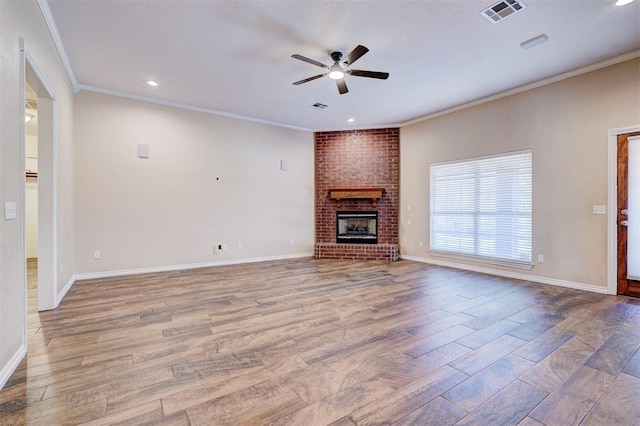 unfurnished living room with ceiling fan, ornamental molding, wood-type flooring, and a brick fireplace