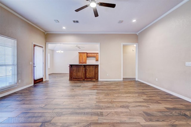 unfurnished living room featuring hardwood / wood-style flooring, crown molding, and a chandelier