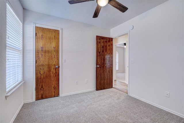 unfurnished bedroom featuring ceiling fan, light colored carpet, and multiple windows