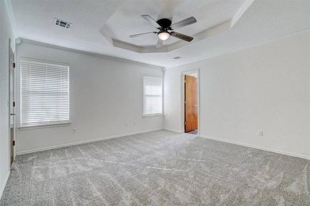 carpeted empty room featuring ceiling fan, a tray ceiling, a textured ceiling, and ornamental molding