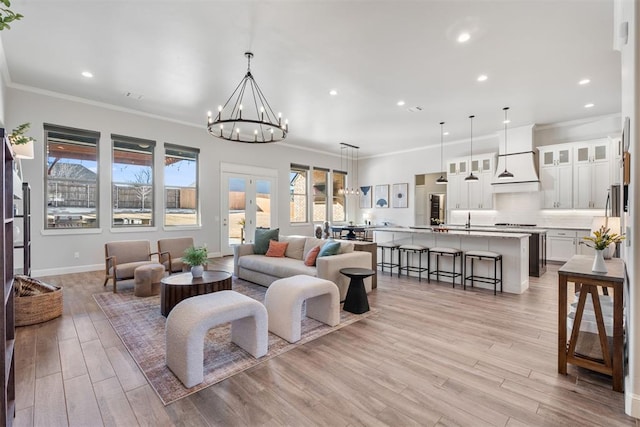 living room featuring a chandelier, light wood-type flooring, plenty of natural light, and ornamental molding