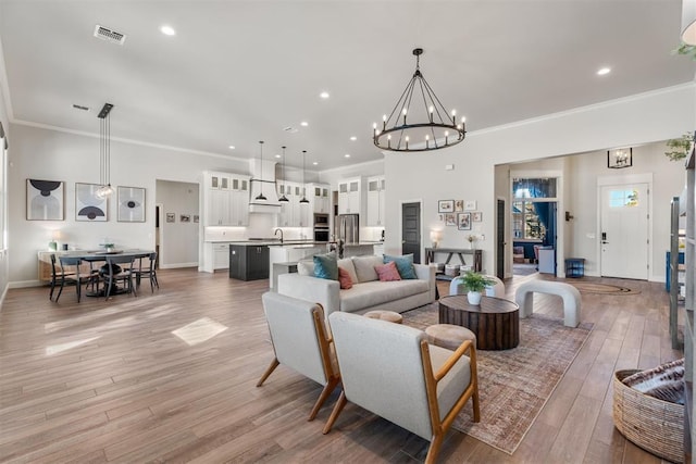 living room featuring hardwood / wood-style floors, ornamental molding, and a notable chandelier