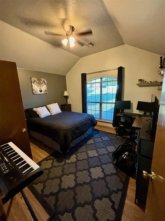 bedroom with a textured ceiling, ceiling fan, lofted ceiling, and hardwood / wood-style flooring