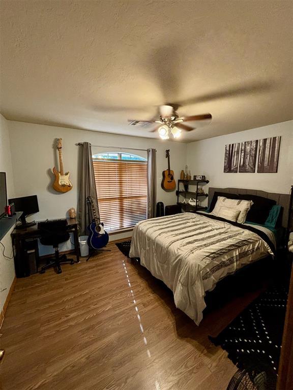 bedroom with ceiling fan, a textured ceiling, and hardwood / wood-style flooring