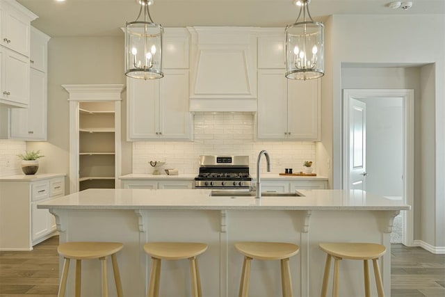 kitchen with stainless steel range oven, an island with sink, and a notable chandelier