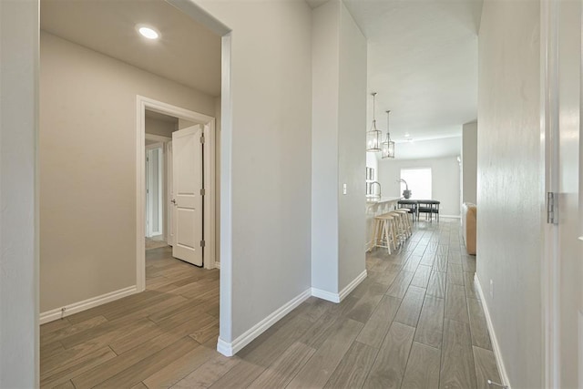 corridor with wood-type flooring and an inviting chandelier