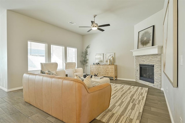 living room featuring ceiling fan, a fireplace, and light wood-type flooring