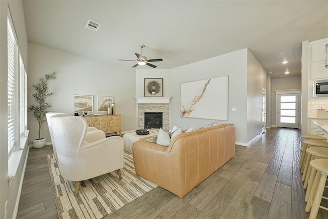 living room with a wealth of natural light, a fireplace, and ceiling fan