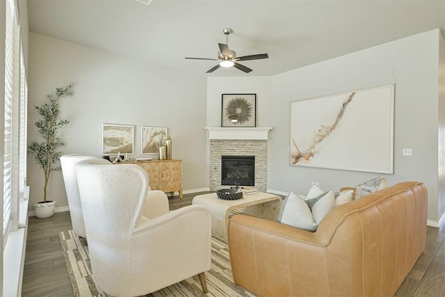 living room featuring hardwood / wood-style flooring, a stone fireplace, and ceiling fan