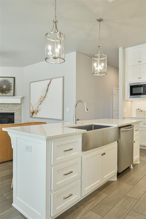 kitchen with white cabinetry, black microwave, sink, hanging light fixtures, and stainless steel dishwasher