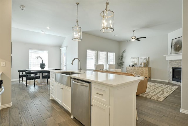 kitchen featuring ceiling fan, dishwasher, white cabinetry, a center island with sink, and decorative light fixtures