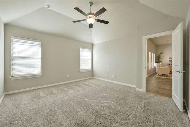 carpeted spare room featuring vaulted ceiling and ceiling fan